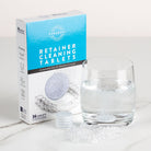 Box of Puradent retainer cleaning tablets with a glass of water and tablet on a white surface